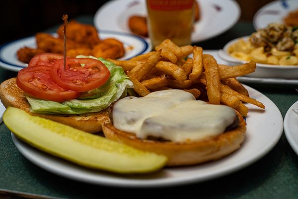 A signature burger with fries and a pickle